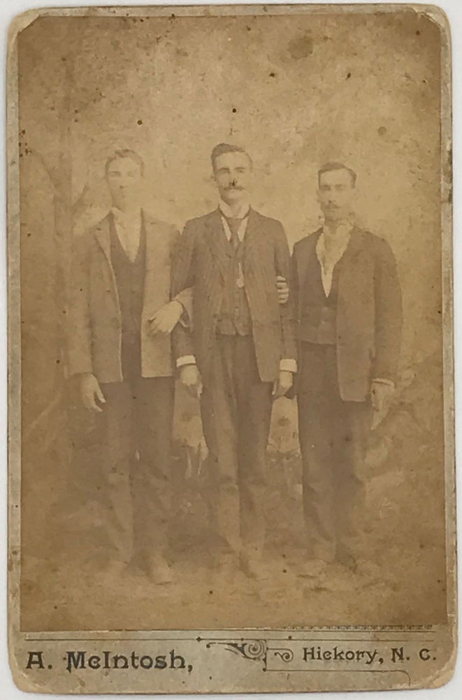 Item #63836 THREE UNIDENTIFIED GENTLEMEN IN JACKETS AND VESTS, posed in a studio, full-length, with arms linked, as pictured in a cabinet card photograph, 5 3/4 x 3 7/8 inches, mounted on larger, heavy card stock, with the photographer's name "A. McIntosh, Hickory, N.C." printed in the card's lower margin. Photograph, Hickory.